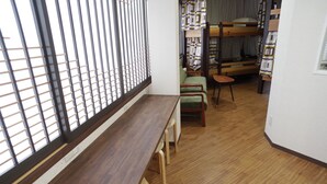 A room with a wooden bench, bunk beds, and a window with vertical blinds.