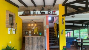 A reception area with a brick wall, a wooden reception desk, and a staircase leading to a covered outdoor area. - Mamatina Hotel (Santa Rosa de Cabal)