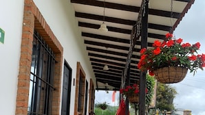 A covered outdoor seating area with wooden chairs and a potted plant. - Mamatina Hotel (Santa Rosa de Cabal)
