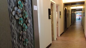Un couloir agrémenté d’un panneau mural décoratif et d’une série de portes portant des numéros d’identification.