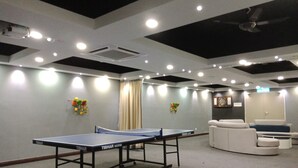 Une pièce avec une table de ping-pong, un canapé et un jeu de fléchettes.