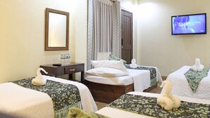 A hotel room with two single beds, a TV, a mirror, a wooden nightstand, and a bathroom with a shower curtain. - Balaibinda Lodge (Coron)