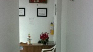 A narrow hallway with a reception desk, framed certificates on the wall, and a potted plant. - Hotel Zafiro Real (Anapoima)