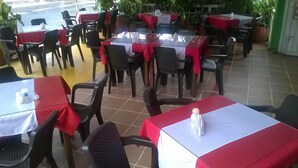 An outdoor restaurant with tables covered in red and white tablecloths, surrounded by chairs. - Hotel Zafiro Real (Anapoima)