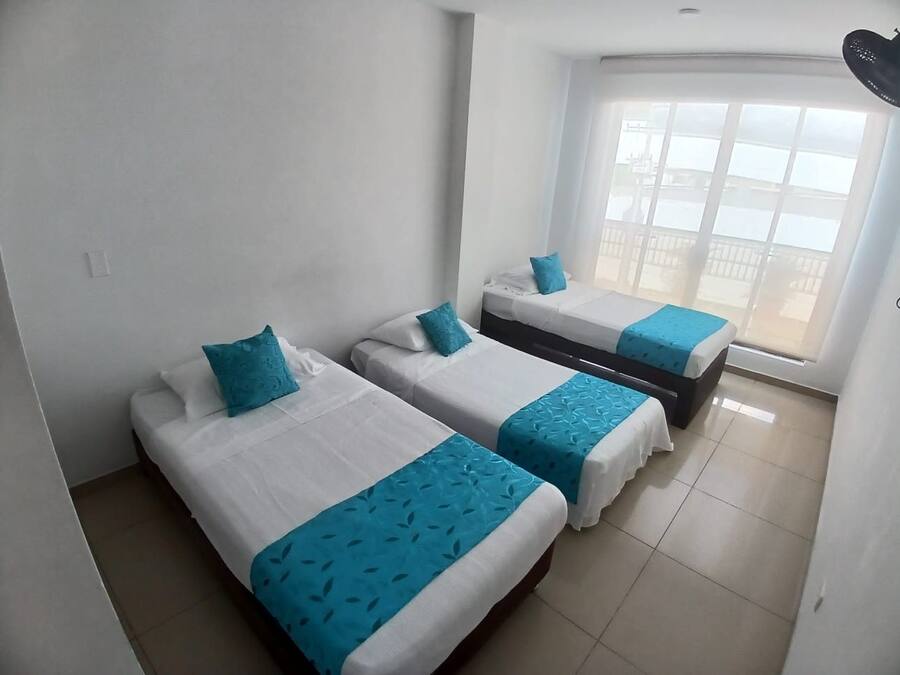 Una habitación de hotel con dos camas, un ventanal con vistas y un ventilador de techo.