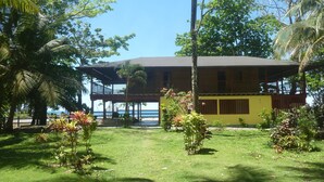 A two-story building with a balcony, surrounded by lush greenery and a clear view of the ocean. - Finca El Regalo (Acandi)