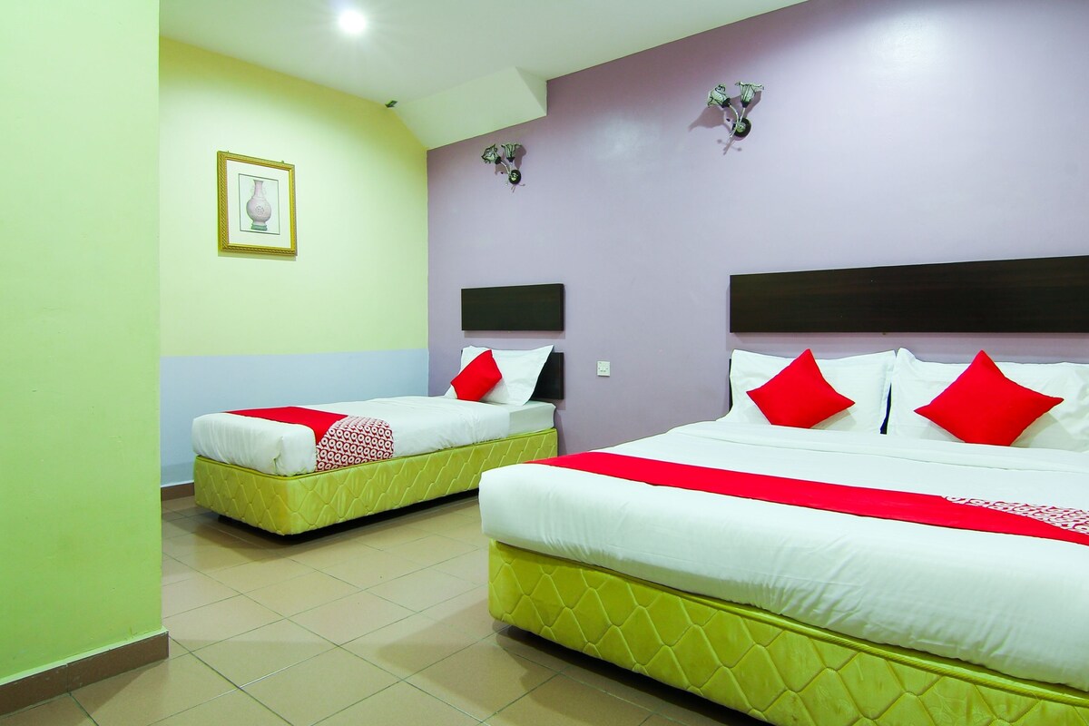 A hotel room with two beds, each with a headboard, a red and white bedspread, and a quilted mattress.