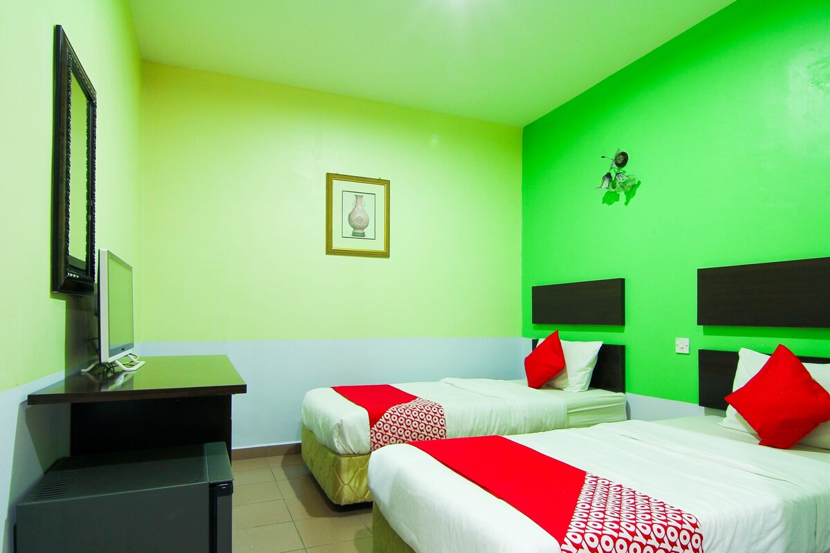 A hotel room with two beds, a desk, and a television.