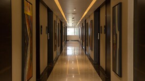 Corredor longo e bem iluminado, com portas em ambos os lados, que leva a um quarto claro no final.