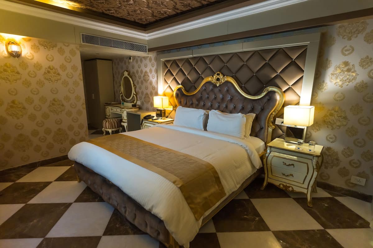 Una habitación de hotel con una cama grande, dos mesitas de noche con lámparas, un aparador y un espejo.