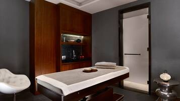 Relax in a serene space with a massage table, tufted chair, and elegant decorative accents.