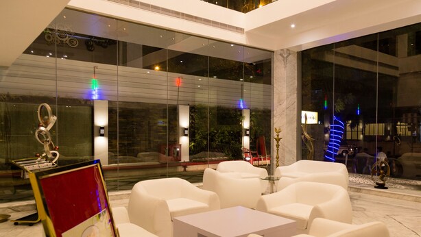 Uma área de estar interna moderna, com sofás brancos e mesa de vidro, com uma placa indicando um restaurante.