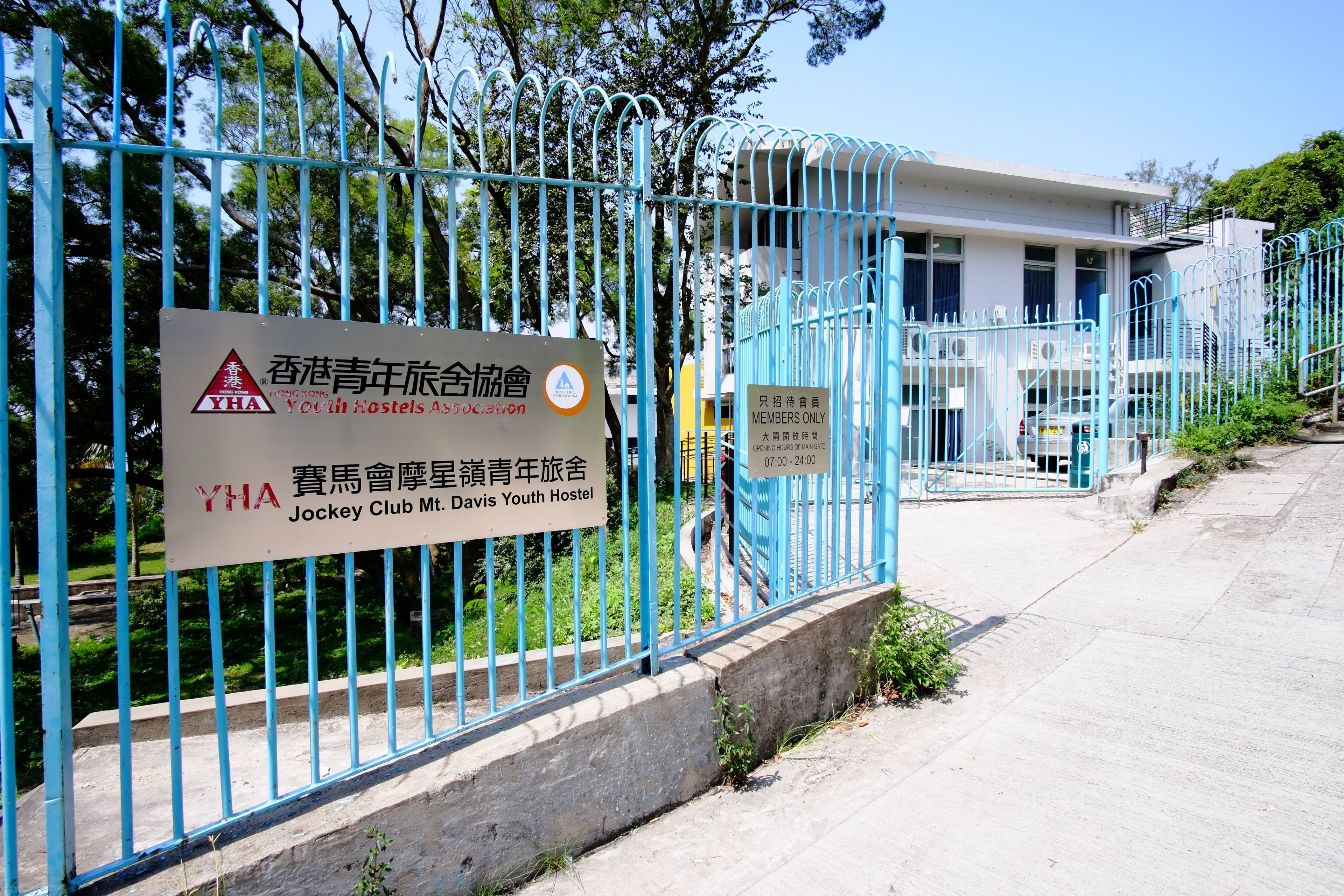 A fenced area with a sign indicating a youth hostel named "Jockey Club Mt. Davis Youth Hostel" and a sign for "Members Only" access from 07:00 to 24:00.