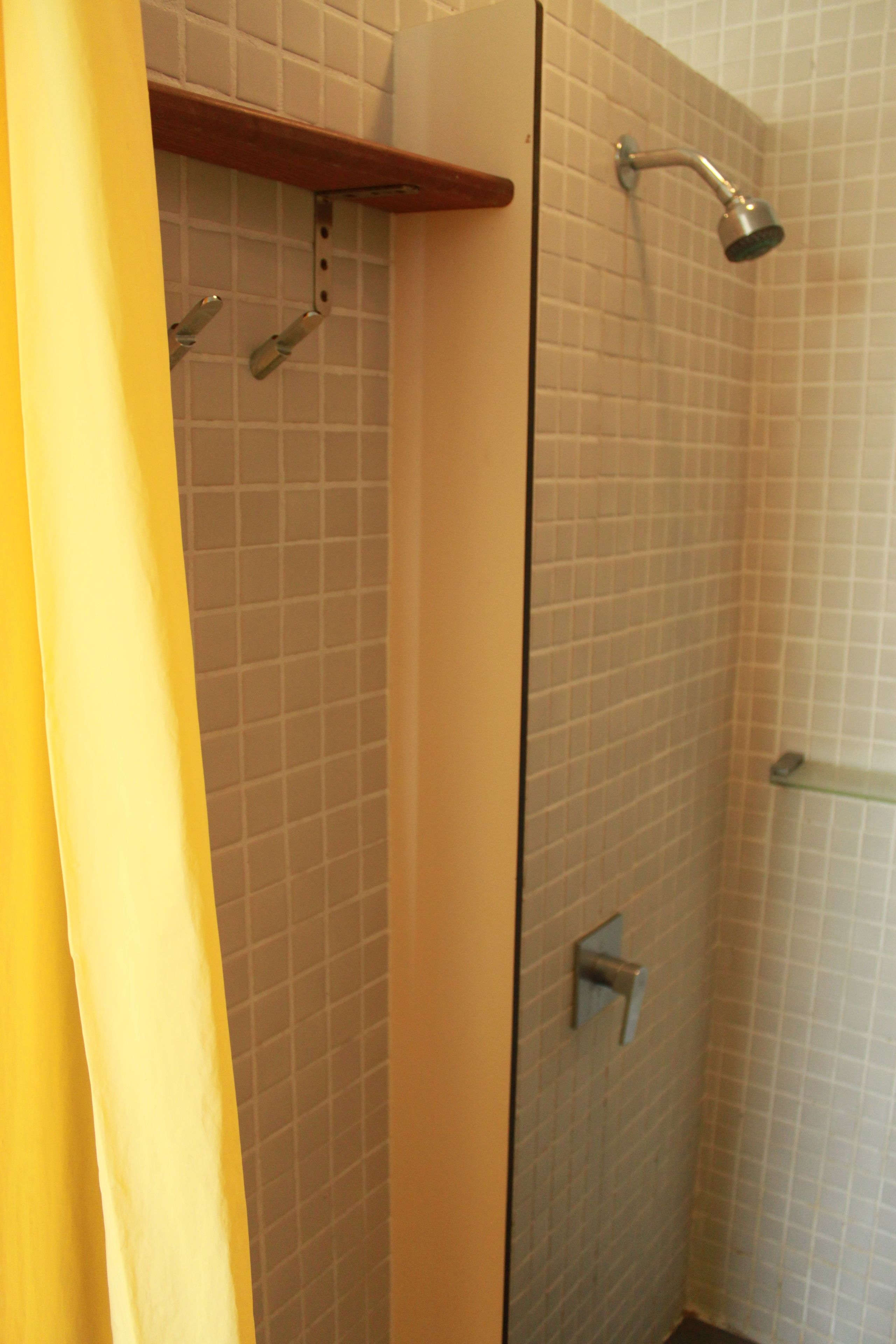 Un área de ducha con pared de azulejos, cabezal de ducha y puerta de cristal.