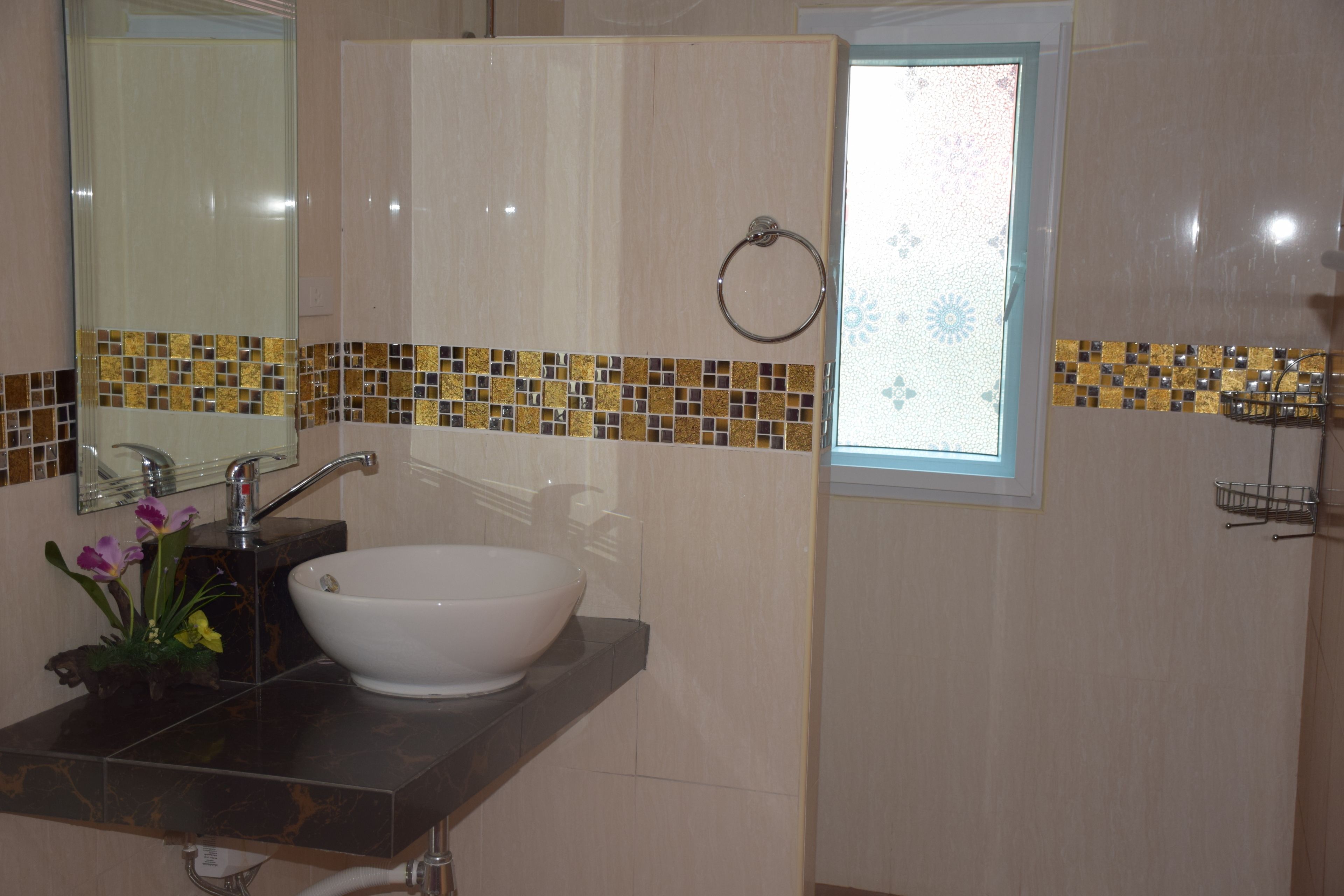 Un baño con un lavamanos blanco, un espejo y una ventana con un borde de azulejos decorativos.