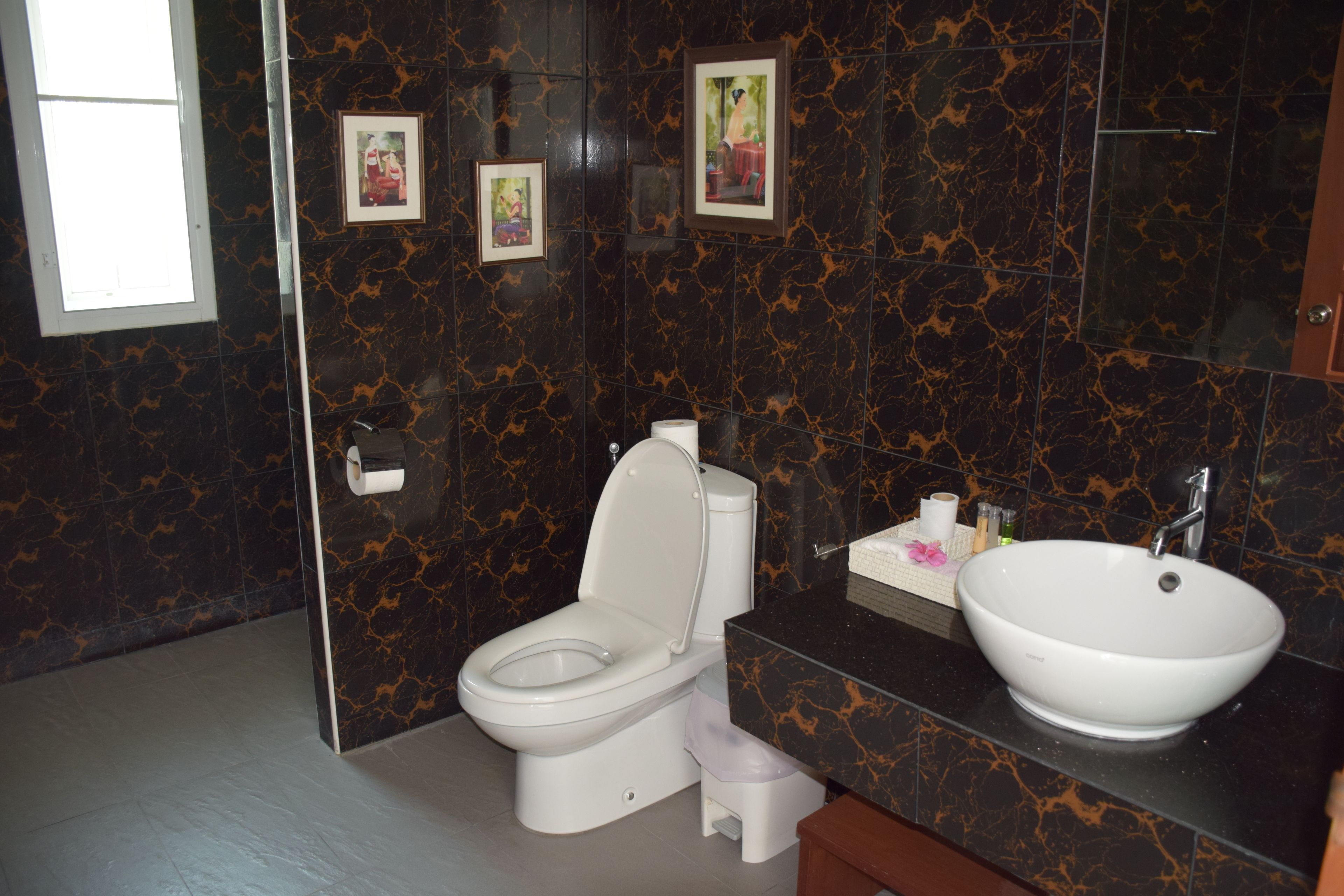 Een moderne badkamer met toilet, wastafel en marmeren wanden.
