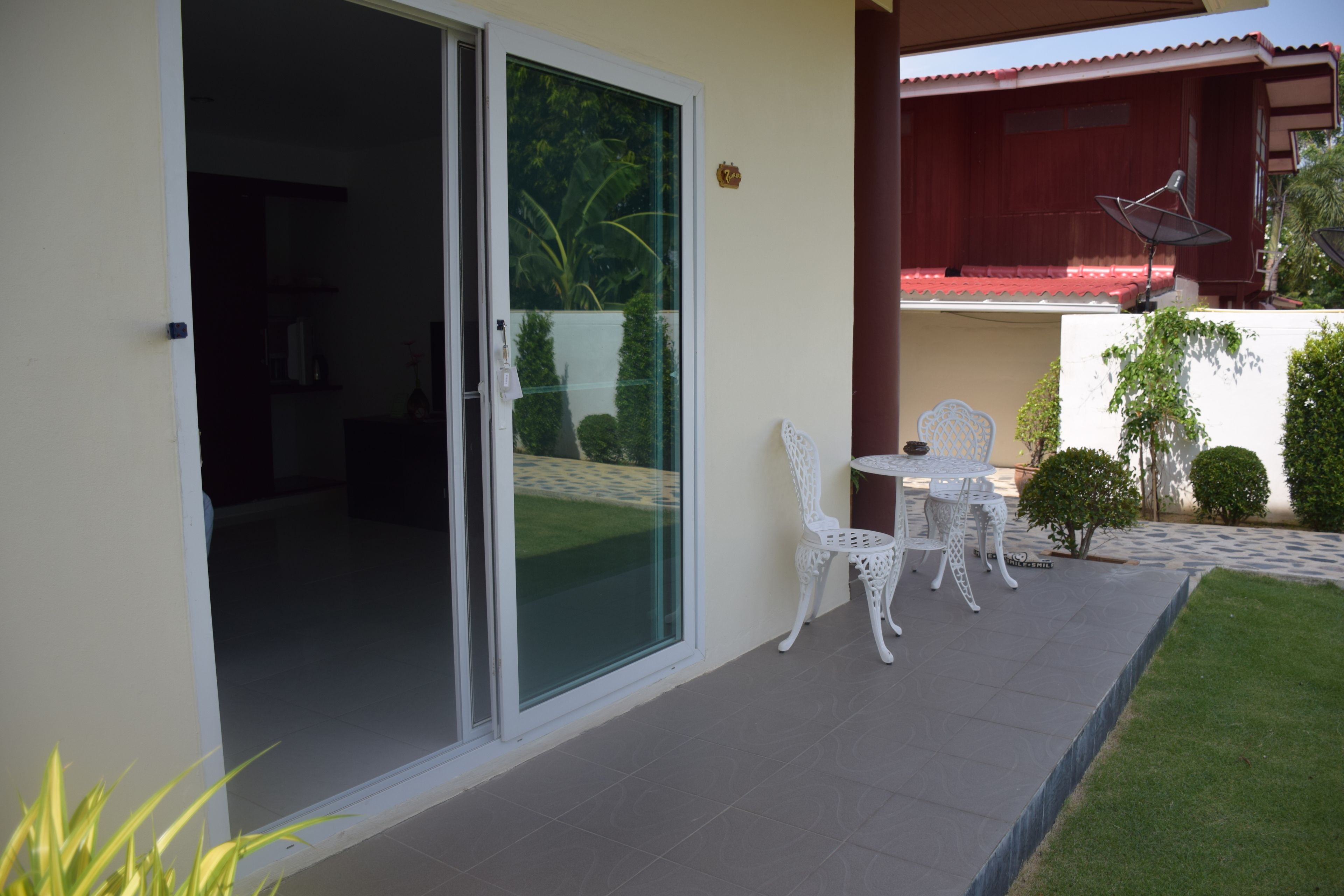 A patio with a table and chairs, a sliding glass door, and a small garden area.