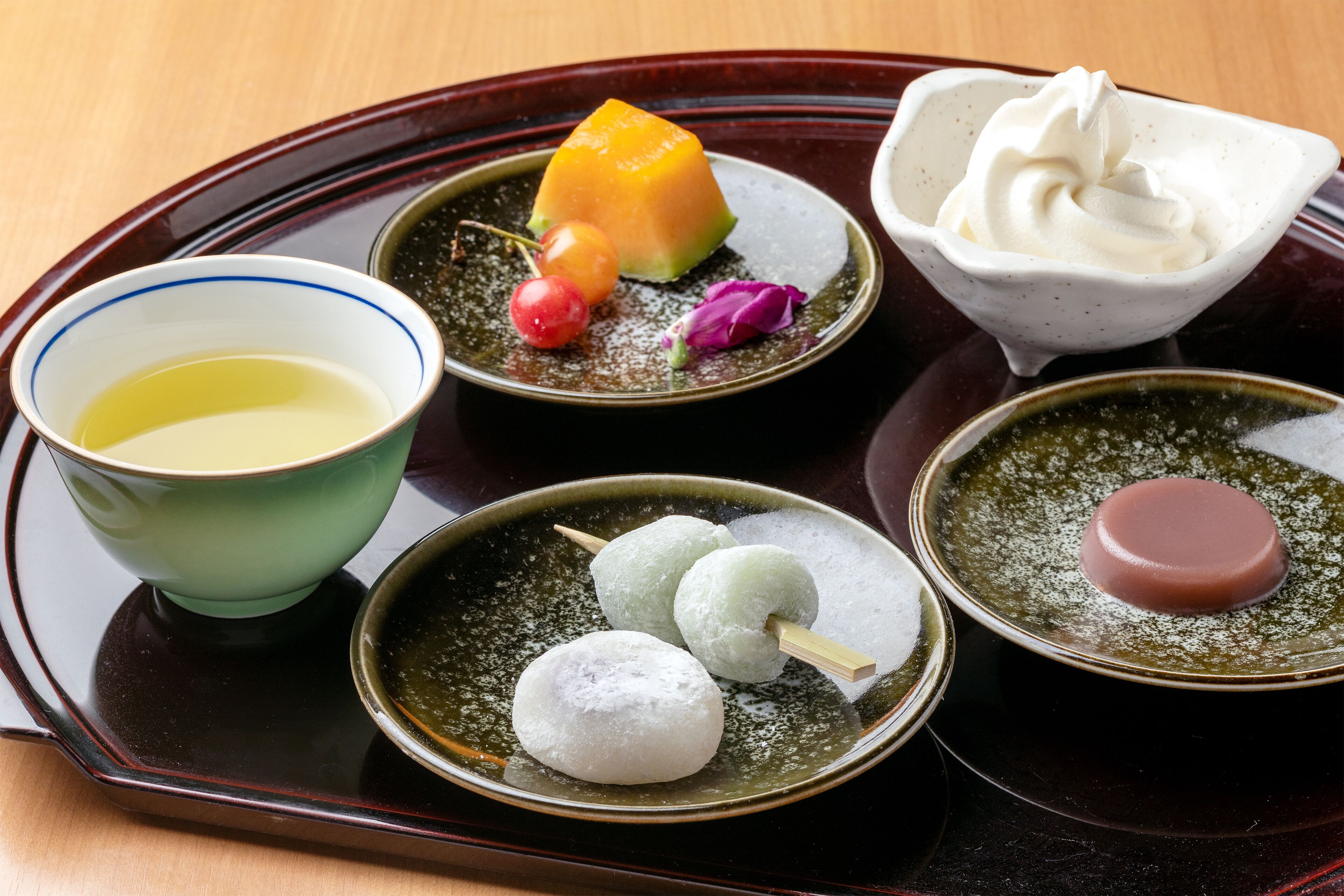 A tray with various Japanese sweets and a bowl of green tea.