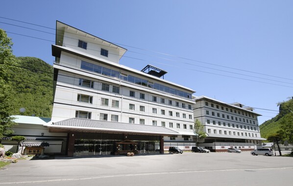 Hotel features a modern design with a flat roof and large windows, set amidst a scenic hilly landscape.