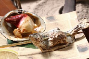 Un plato de mariscos con una rodaja de limón sobre una tabla de madera.