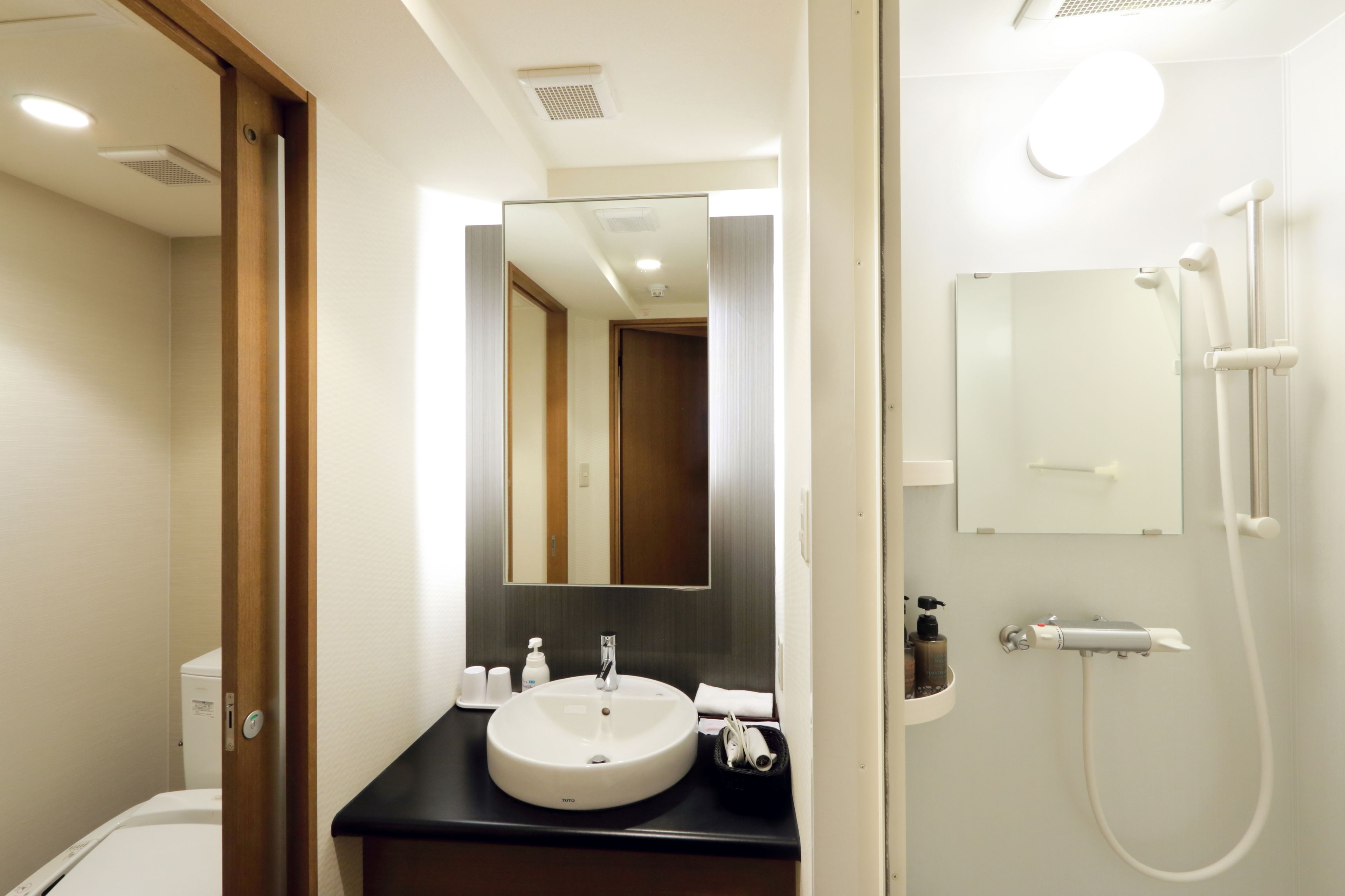 Un baño moderno con lavamanos, espejo y ducha.