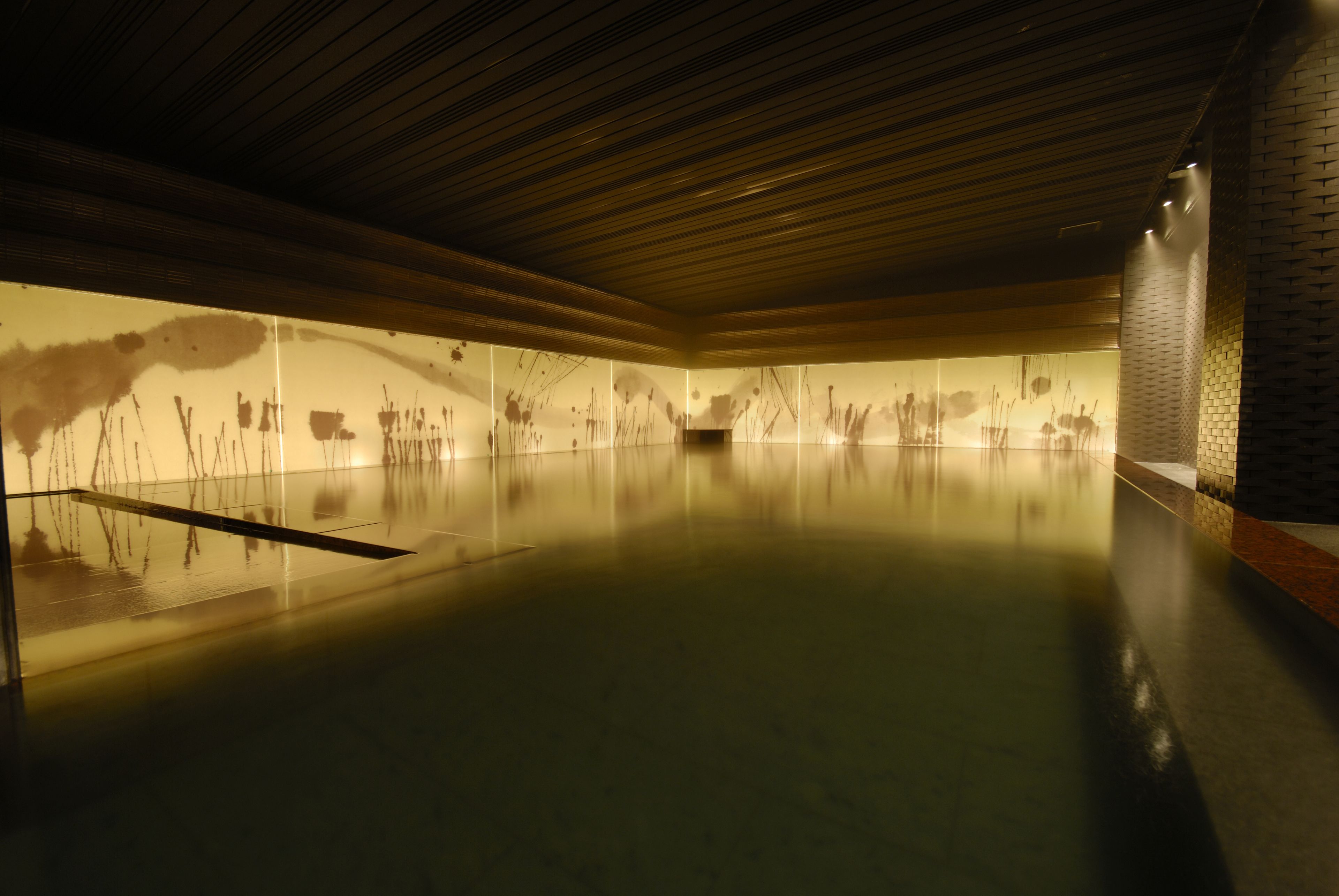 A spacious indoor area with a polished floor and a wall with abstract art.