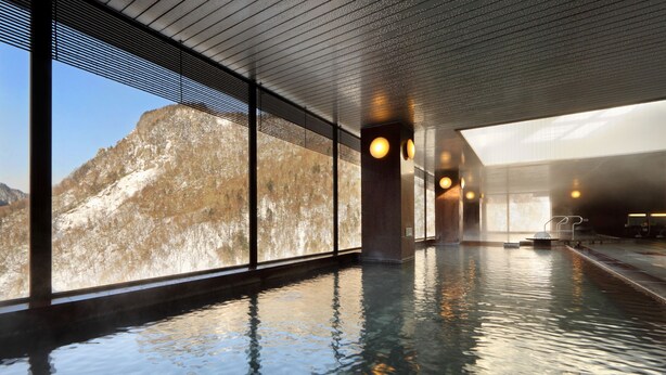 Une piscine intérieure dotée de grandes fenêtres donnant sur un paysage montagneux.