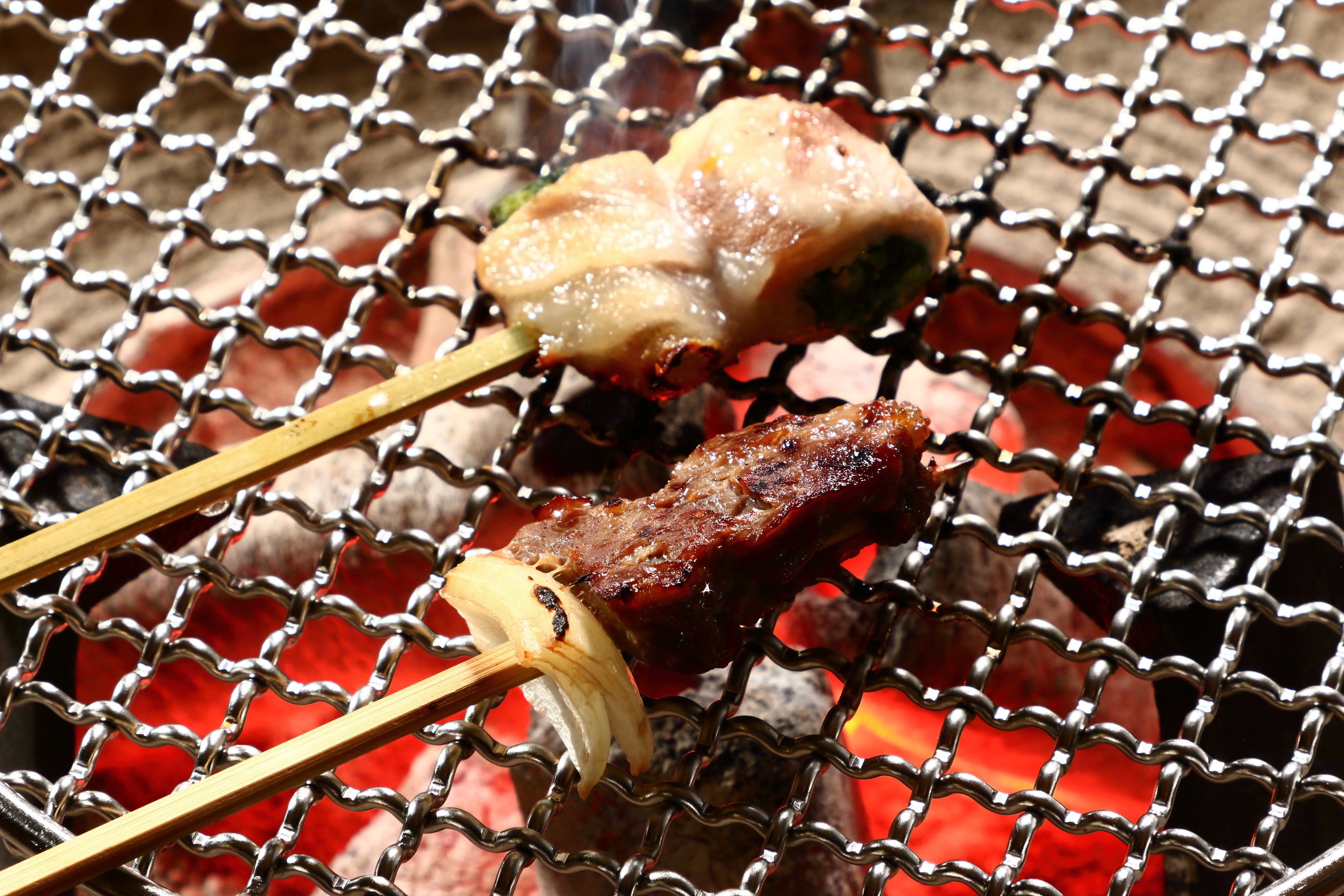 A grill with skewers of meat and vegetables over glowing coals.