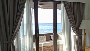 Una habitación con puerta de vidrio corredera que da a un balcón con vista al mar.