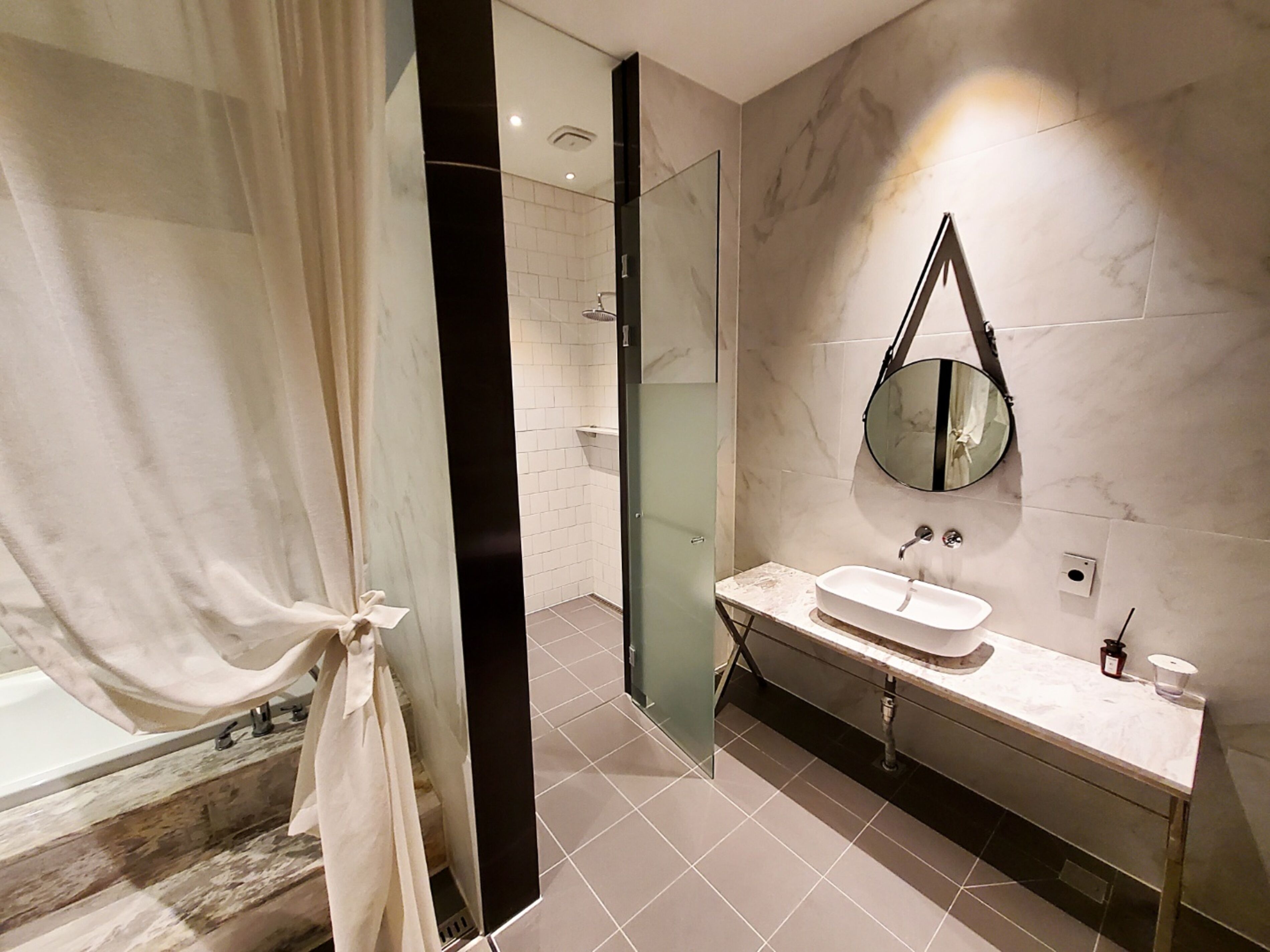 Un baño moderno con cabina de ducha de vidrio, tocador con lavamanos y un espejo grande.