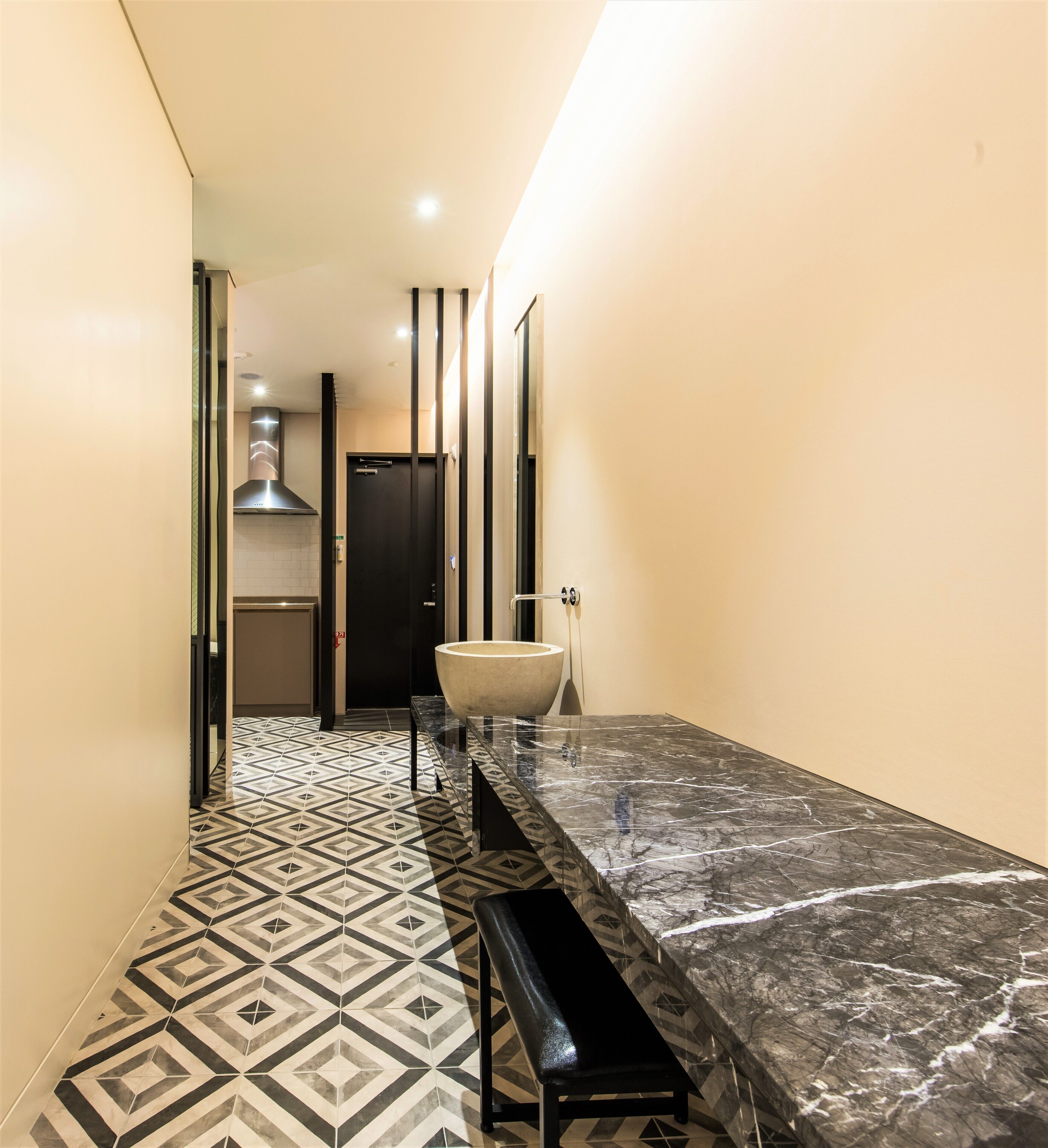 A hallway with a marble countertop and a large sink.