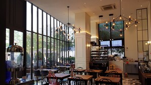 A restaurant with large windows, wooden tables, and a variety of chairs. - Hotel Stendhal (Daejeon)
