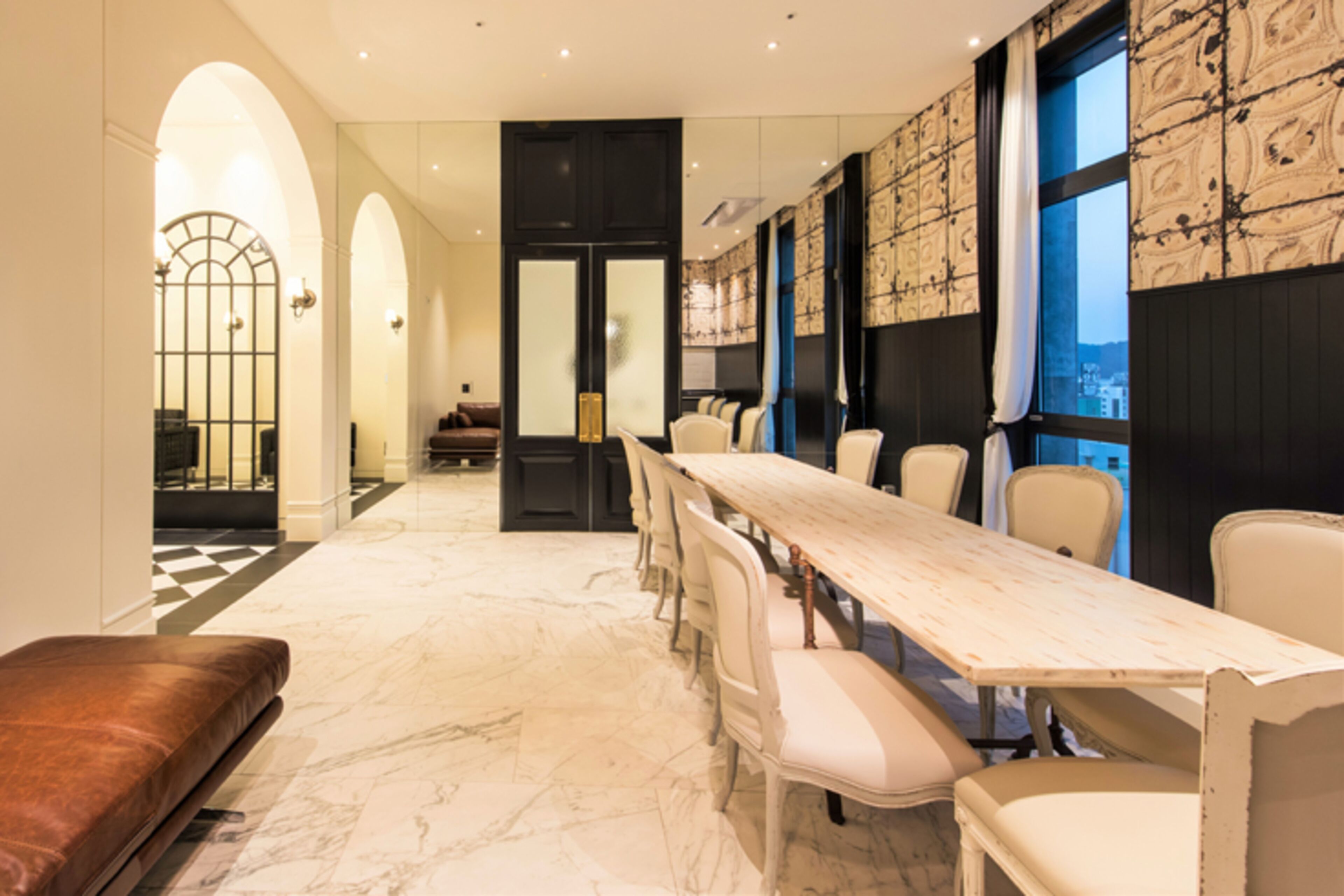 A conference room with a long table, white chairs, and a marble floor.