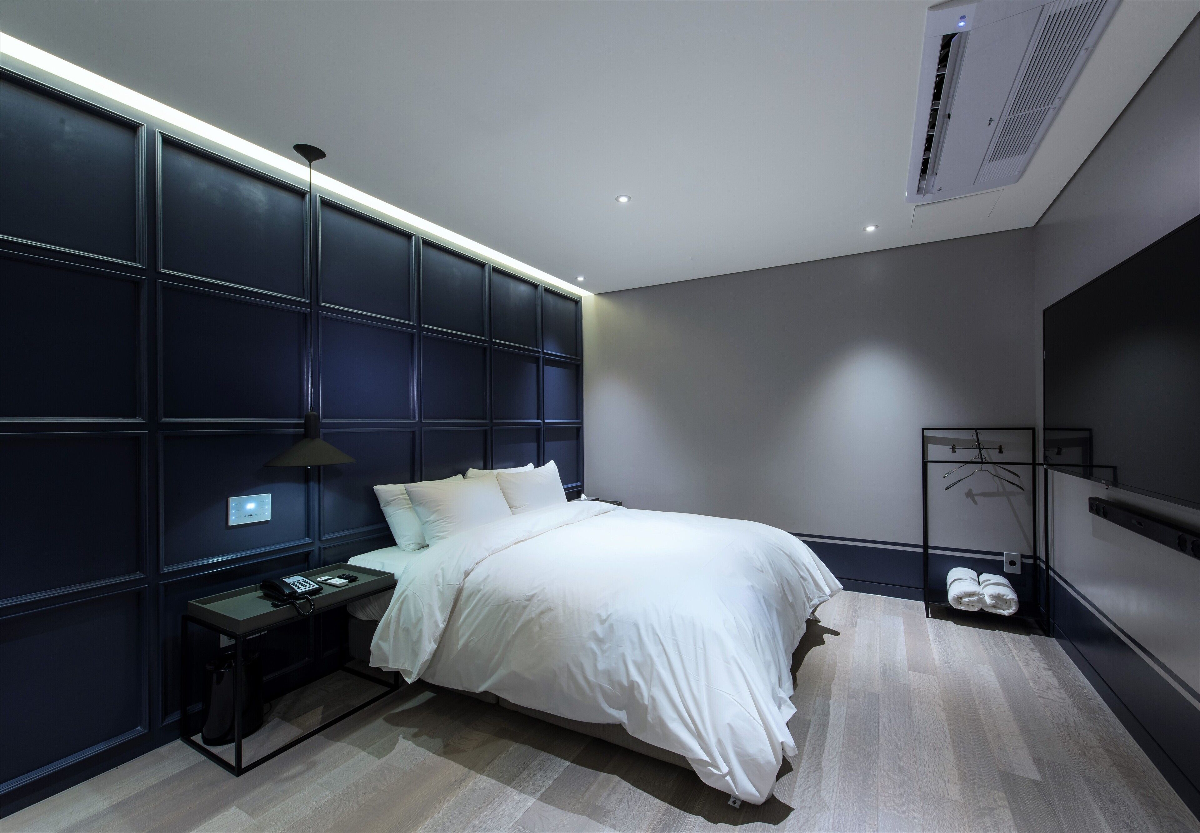 Une chambre moderne avec un grand lit, une table de chevet et un radiateur fixé au mur.