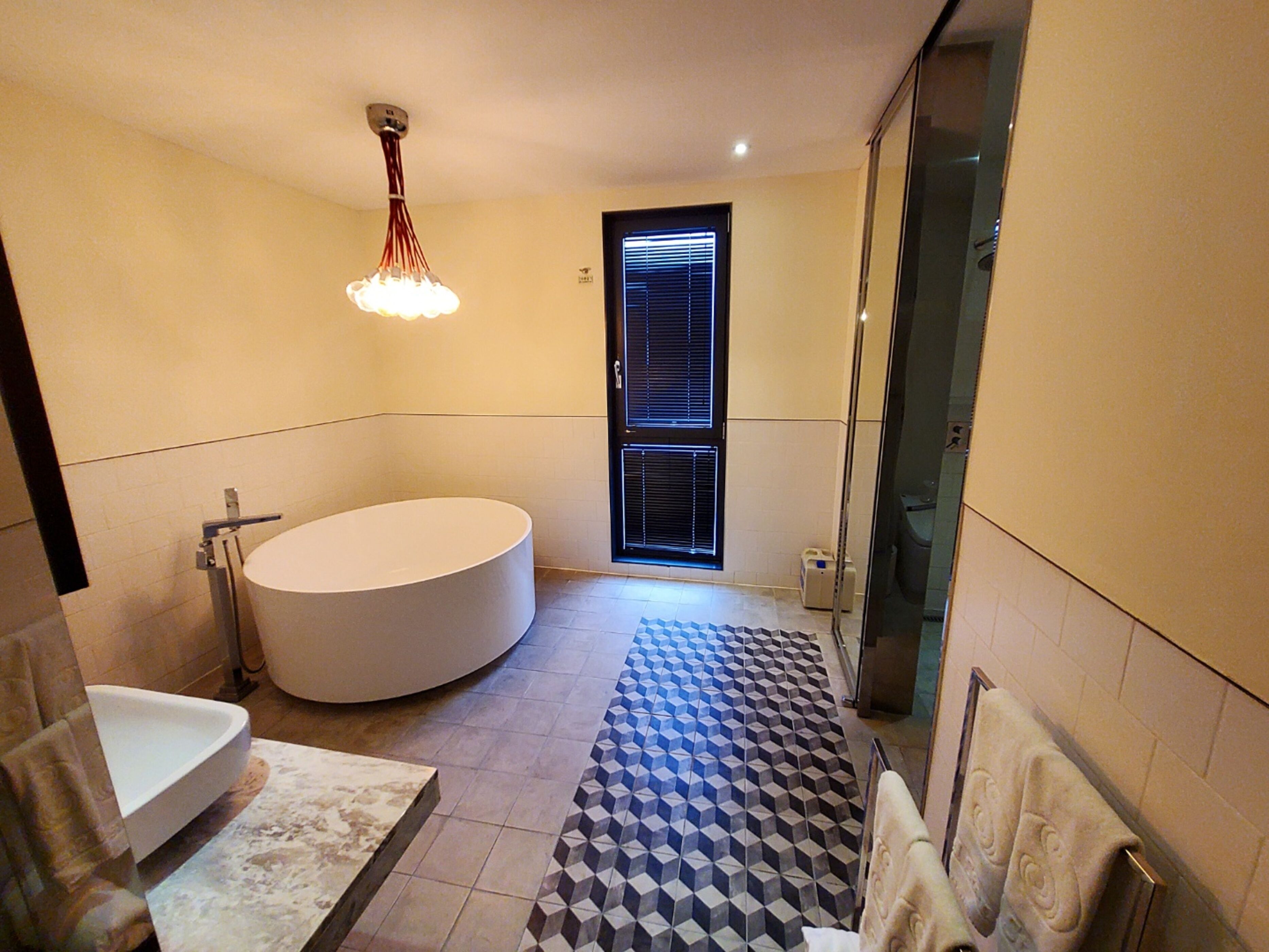Un baño moderno con una bañera independiente, un espejo grande y un suelo estampado.