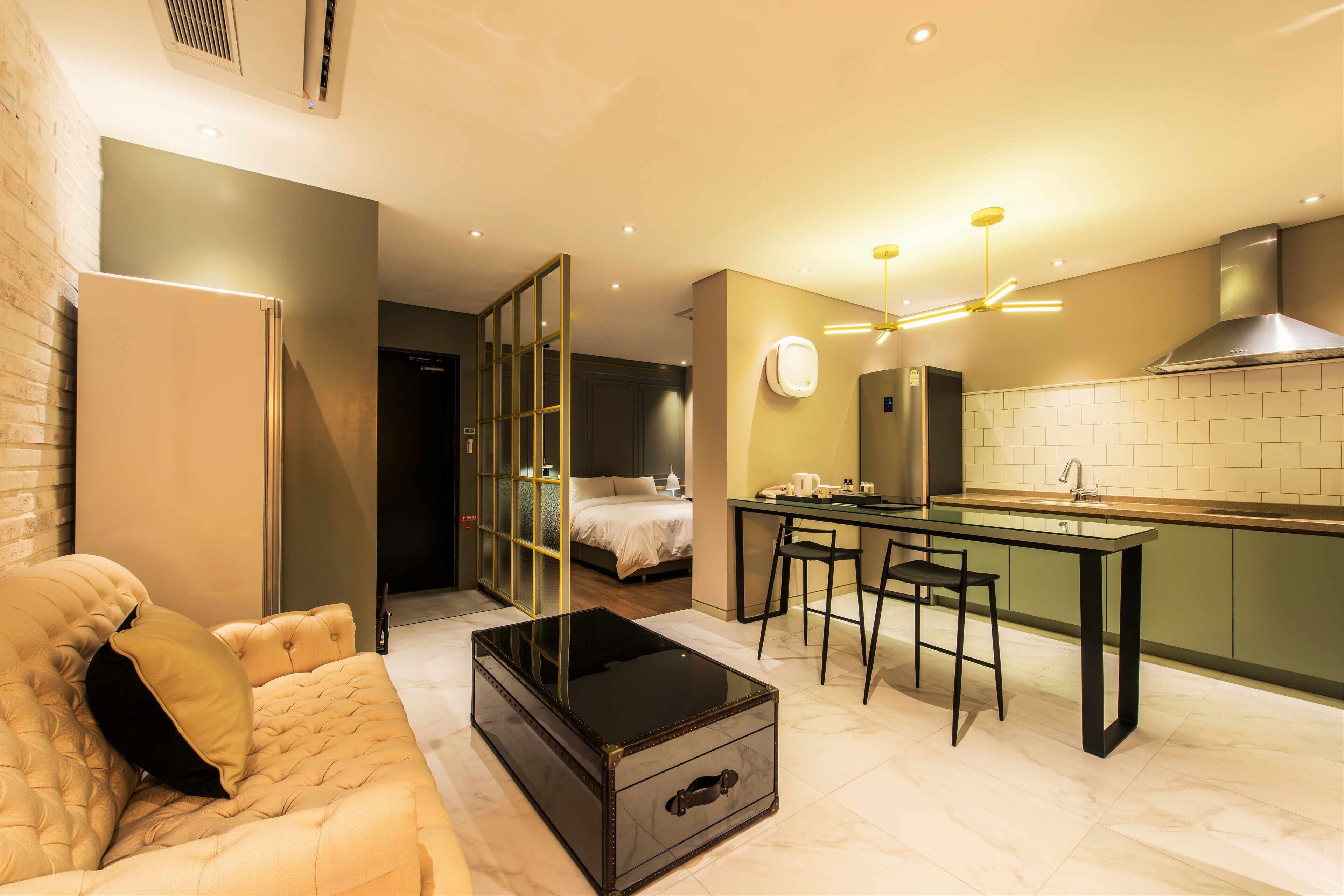 A modern kitchen with a dining area, a sofa, and a bed.