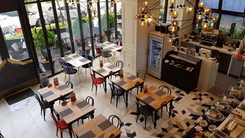 Un restaurant doté de nombreuses tables et chaises, d’un coin café et d’un tableau affichant le menu.