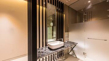 A modern bathroom with a large mirror, a white sink, and a glass shower enclosure.