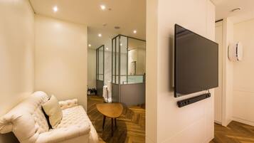 A modern living room with a flat-screen TV mounted on the wall, a plush sofa, and a wooden floor.