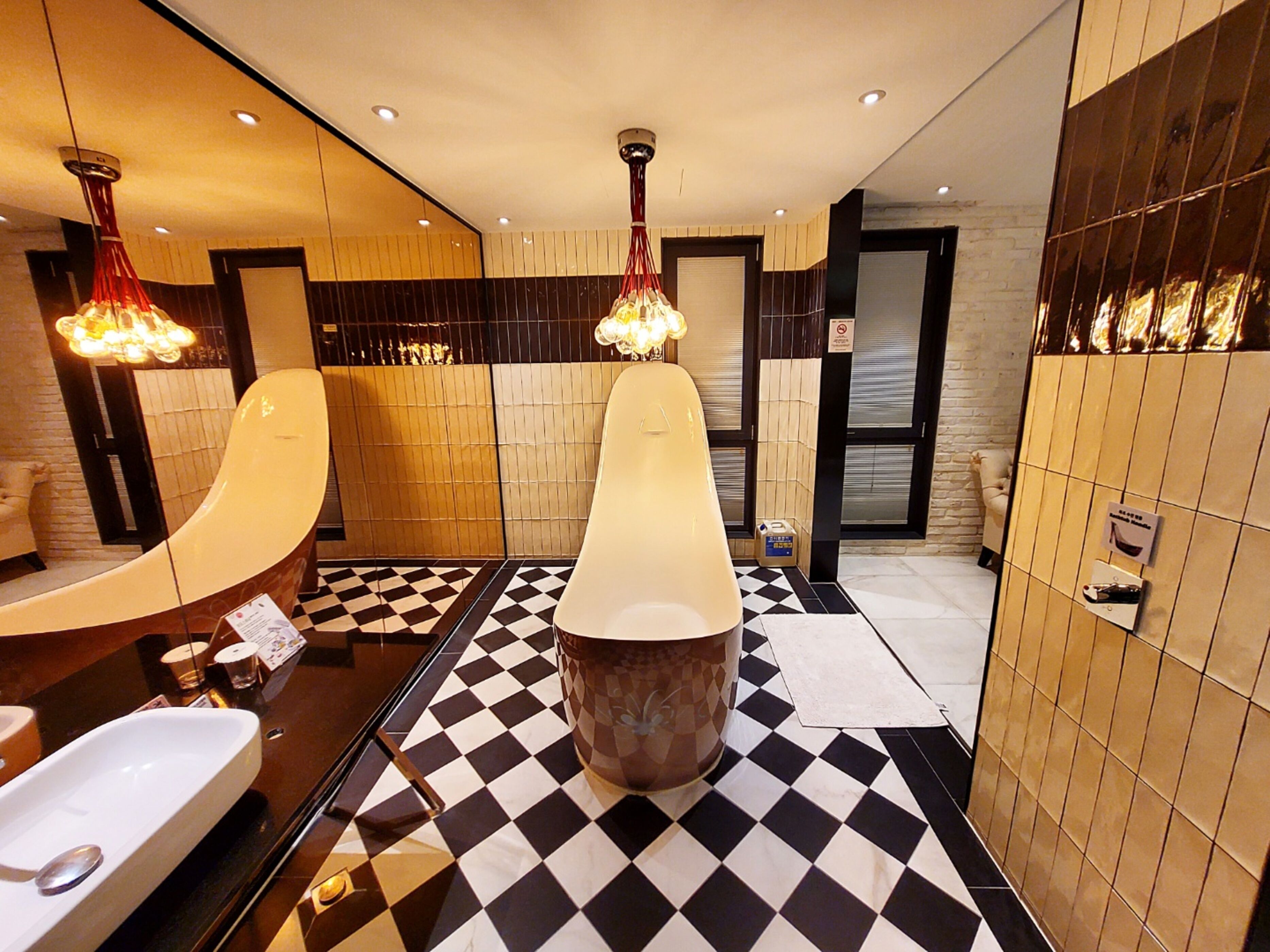 A modern bathroom with a checkered floor, a large mirror, and two pendant lights.