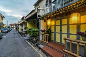 A narrow street lined with traditional buildings, featuring balconies with railings and potted plants. - Ohana House @15 Kuli (Malacca City)