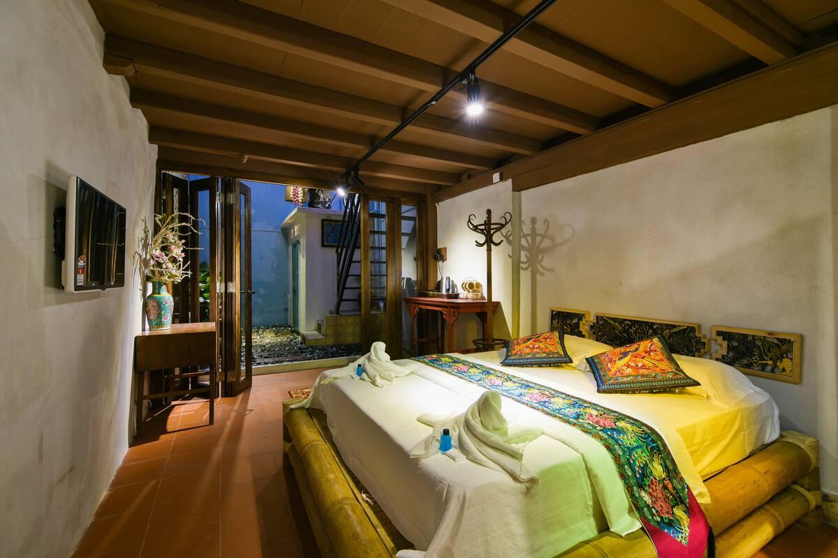 A bedroom with a bed, a wooden bench, a small table, and a wall-mounted coat rack.