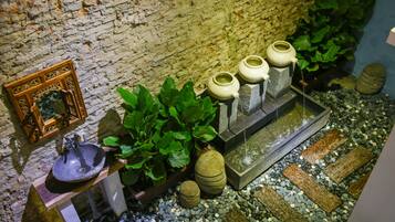 A rustic bathroom with a stone sink, decorative vases, and lush green plants.