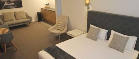 Une chambre d’hôtel avec un grand lit, un canapé, une petite table et un meuble.