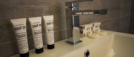 A bathroom with a white sink, three bottles of soap, and a bar of soap.