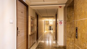 Ein Hotelgang mit einer Holztür mit der Aufschrift '301', einem Rauchverbotsschild und einem Aufzug mit digitaler Anzeige.