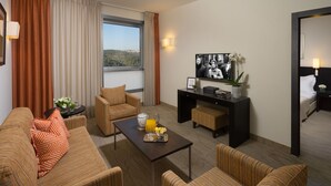 Une chambre d’hôtel comprenant un canapé, des fauteuils, une table basse, un bureau et un lit.