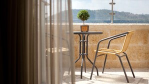 Un balcon avec un fauteuil en osier, une petite table et un pot de fleurs.