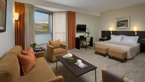 Une chambre d’hôtel avec un lit, un canapé, un bureau et une vue sur la ville.