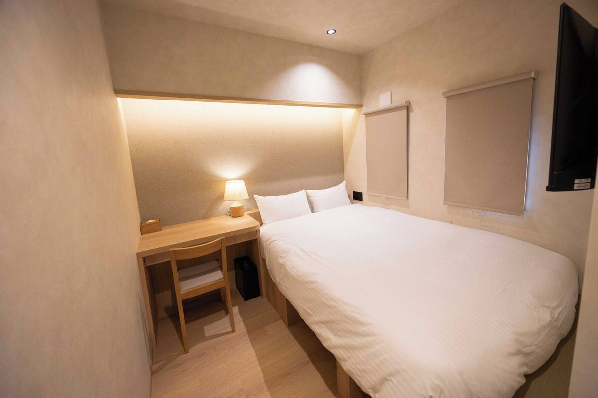 A bedroom with a bed, a desk, and a chair.